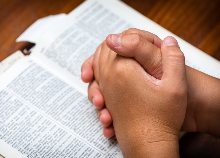 Homeschool christian with praying folded hand on bible