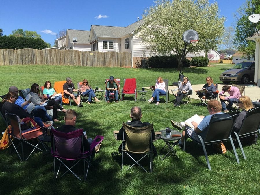 adults meeting in a circle of lawn chairs in a grassy backyard learning through the Classical Conversations Plus curriculum