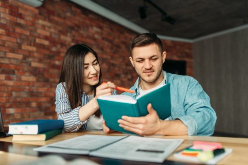 University students reading textbook together. People with book prepares for exams, joint project